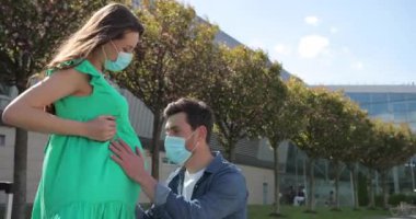 Beyaz bir adam karısının karnından yeni doğmuş bebeğini öpüyor ve dinliyor. Aile çifti birlikte vakit geçiriyor. Aile ilişkileri ve salgın sırasında anne sağlığı kavramı