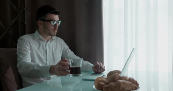 Alkalmi ruhás üzletember, aki laptopon dolgozik és kávét iszik. — Stock videók