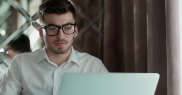 Zakenman werkt aan tafel met laptop. Een man die tee drinkt. Achter hem is een mooie spiegelwand.. — Stockvideo