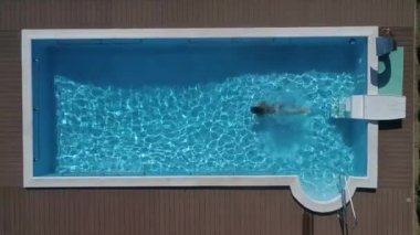 Yaz tatilindeki genç bir kadın sıcak ve güneşli bir günde serinlemek için önce açık mavi havuz suyuna atlıyor. Siyah bikinili kız lüks oteldeki boş havuza dalıyor..