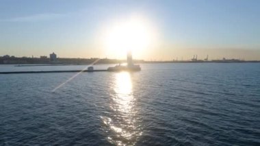 Yavaşlamalar. Denizde bir deniz feneri var. Arkasında güneş vardı. Güneş ışınları suyun üzerinde parlıyor. Video bir İHA 'da çekildi. Gün batımı. Gün doğumu