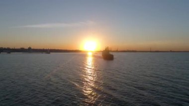 Gemi denizde yelken açıyor. Deniz fenerinin yanında. Uçan kuşlarla güzel bir gün batımı. Turuncu ve altın rengi mavi gökyüzü. Altın deniz.