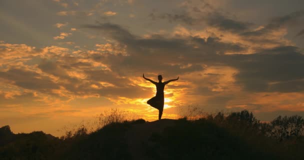 Joven relajándose al aire libre, hace posición de árbol. un hombre balanceado en una pierna al atardecer. En armonía con la naturaleza. — Vídeo de stock