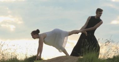 Çift dışarıda yoga yapıyor. Ebedi uyum arayışı. Zihin ve beden. Akroyoga
