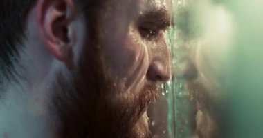 Kızıl sakallı ve depresyonlu mutsuz adamın yakın plan portresi ne yazık ki duştaki cama yaslanıyor..