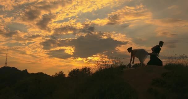 Een paar doet buiten aan yoga. Eeuwig zoeken naar harmonie. Geest en lichaam. Acroyoga. Op de achtergrond van de televisie tover, prachtige natuur, bewolkte lucht en prachtige zonsondergang. — Stockvideo