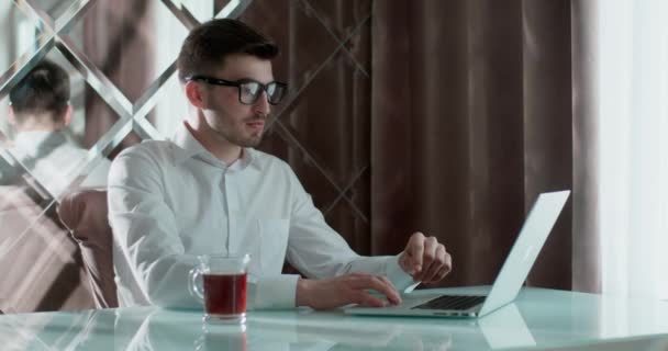Junger Mann mit Laptop studiert Online-Arbeit. Er ist müde. Seine Frau geht auf ihn zu und schließt den Laptop. Ehefrau umarmt ihren Mann. — Stockvideo