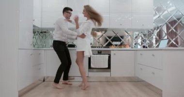 Gençler mutfakta sarılıp dans ediyorlar. Çift mutlu ve komik. Eğleniyorlar.