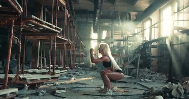 Blondynka fitness model wykonywania przysiadów i podniesienie rąk w pobliżu jej twarzy podczas treningu — Wideo stockowe