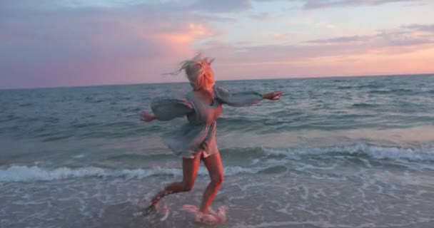 Aantrekkelijk blond loopt langs het strand. Mooie jonge vrouw die plezier heeft aan de kust. Zomer. Emotie. — Stockvideo