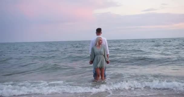 Jong stel dat aan zee in het water staat, rug aan rug — Stockvideo