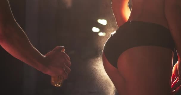Крупним планом масляний спрей на тонованих сідницях і задній частині моделі жінки перед фотосесією . — стокове відео