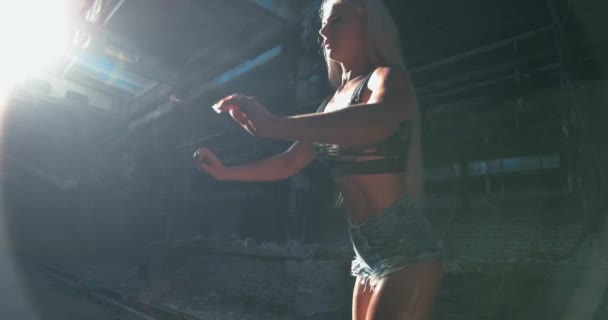 Nahaufnahme eines attraktiven kaukasischen Fitnessmodells beim Beinschwung und beim Stretching nach vorne im Hintergrund der Fabrik — Stockvideo