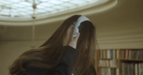 Studente donna, sede della biblioteca. Affascinante ragazza si rilassa ascoltando la musica nelle cuffie — Video Stock