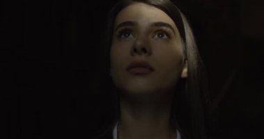 Kadın öğrenci, karanlık. Büyüleyici kız karanlık kütüphanede duran ışığa bakıyor.