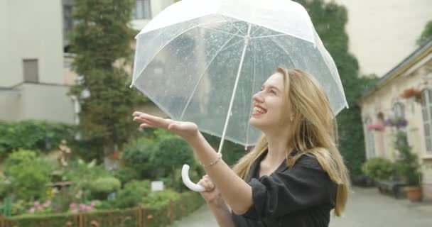 Charmig blond kvinna njuter av sommar regn promenader med paraply — Stockvideo
