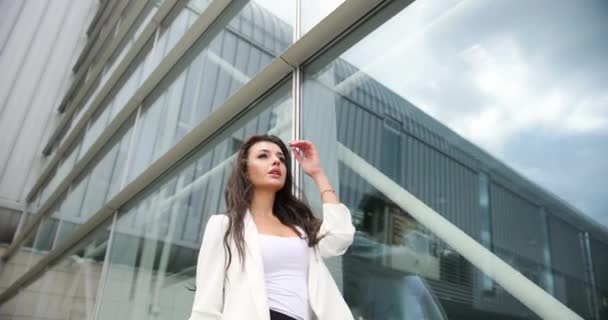 4k. Zeitlupe und Zeitraffer. Phantasievoll gekleidete junge Geschäftsfrau in schwarz-weißer Kleidung posiert vor einem modernen Glasgebäude im Freien — Stockvideo