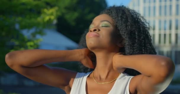 Yeşil göz farı ve tarafsız ruj sürmüş güzel Afro-Amerikalı kız siyah kıvırcık saçlarını sallıyor.. — Stok video