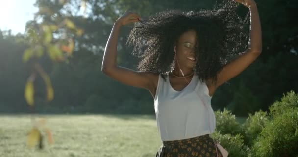 Portret Piękny Młody Afro American Girl Pretty Szczęśliwie Uśmiechnięty Energicznie Aktywnie Taniec Uścisk dłoni Dotknięcie kręcone włosy Słuchanie Korzystanie z muzyki Słuchawki Outdoor Garden 4k Slow Motion — Wideo stockowe