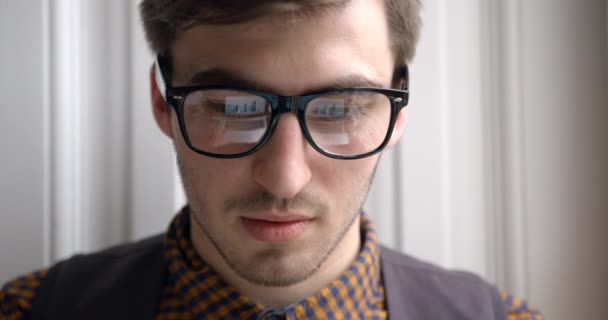 Zbliżenie portretu zmęczonego przystojnego biznesmena pracującego nad laptopem, a potem zdejmującego okulary. Odbicie diagramów i grafiki w okularach. — Wideo stockowe