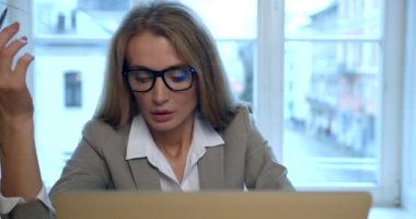 Bilgisayarda çalışan yorgun ve gergin sarışın iş kadınının ön görüntüsü. Ofiste bir şeyler yazıyor..