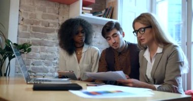 Laptop, tablet ve ofiste grafiklerle çalışan üç çok yönlü iş adamının takım çalışması. 4k.