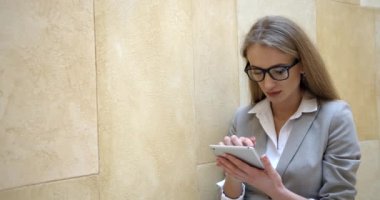 Genç sarışın kadın şaşırdı ve tabletle mesajına sinir bozucu bir şekilde cevap verdi. Yakın plan portre.