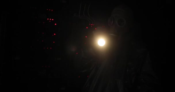 Hombre en una máscara de gas y overoles brilla una linterna en el mando a distancia. botones rojos se encienden en el panel de control. — Vídeos de Stock