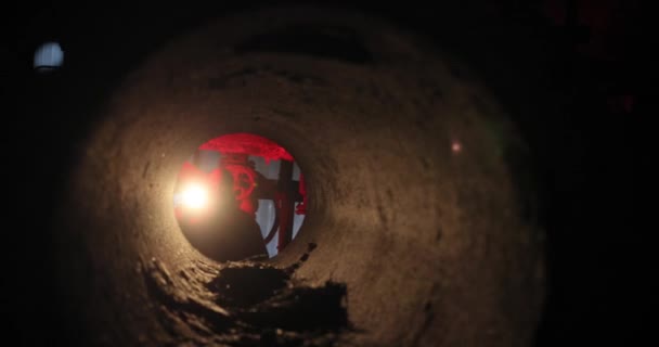 Alla fine del tunnel una sagoma di un uomo con una maschera antigas con una torcia in mano. luce rossa alla fine del tunnel. — Video Stock