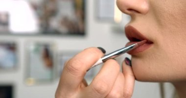 Makyaj sanatçısının el görüntüsü yakın plan. Bej ruj sürüyor. Model ağız fırçasıyla..