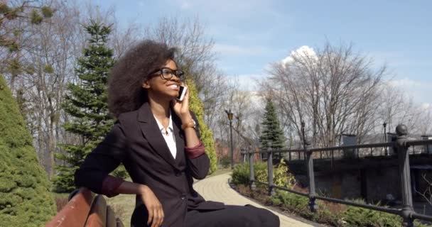 Seitenansicht Porträt Glücklich Schön Attraktiv Junge Afrikanische Geschäftsfrau Brille Anzug Aktiv Sprechen Handy Sitzbank Park Garden. — Stockvideo