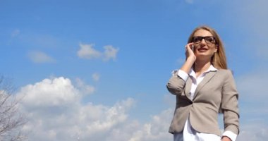 Portre Çekici Sarışın İş kadını Gözlüklü Bej Takım Elbiseli Mutlu Konuşan Cep Telefonu Arka planı Gökyüzü 4k Konuşma Mutluluğu.