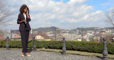 Afro-Amerikan iş kadınının arka plandaki cep telefonuyla konuşurken gülümseyen ve gülen uzun boylu görüntüsü..