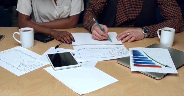 Detailní pohled na ruce mnohonárodních podnikatelů. Samci běloši kreslí tu grafiku. Obchodní koncept. Stůl potažený notebookem, tabletem, diagramy a poháry. — Stock video