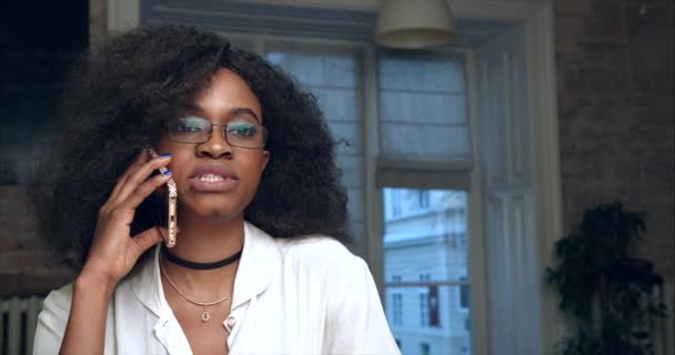 Gros plan sur la femme d'affaires afro-américaine sérieuse en lunettes parlant via le téléphone portable au bureau. 4k. — Video