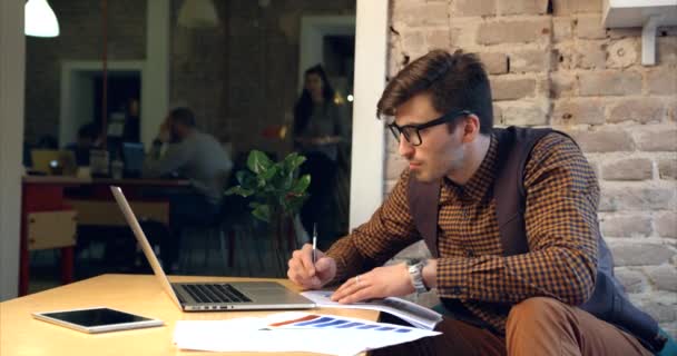 Handosme fiatal üzletember szemüvegben ír és dolgozik a laptopnál az irodában.. — Stock videók
