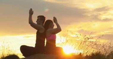 Gün batımında kumsalda yoga yapan çift. Lotus pozu açılıyor. Ruhta huzur ve sessizlik ve doğayla uyum. Güzel gün batımı.