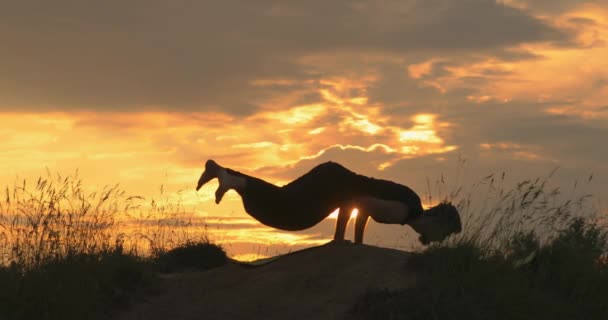 Ο αθλητικός τύπος κάνει γιόγκα το ηλιοβασίλεμα. Ασκήσεις ισορροπίας βραχίονα, asana Astavakrasana. Ασύμμετρη ισορροπία χεριού. Θέση οκτώ γωνιών. — Αρχείο Βίντεο