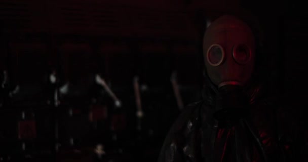 Un homme dans un masque à gaz regarder rapidement à la caméra dans la pièce sombre avec la lumière rouge, fermer. Concept d'Apocalypse. — Video