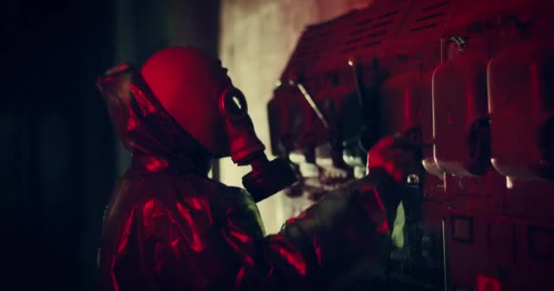 Тривога блимає червоне світло. людина в газовій масці стоїть біля стіни з вимикачами і вимикає їх — стокове відео