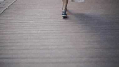 Kız cadde boyunca yürüyor. Yeni mavi ve beyaz ayakkabıların yakın çekim görüntüsü.