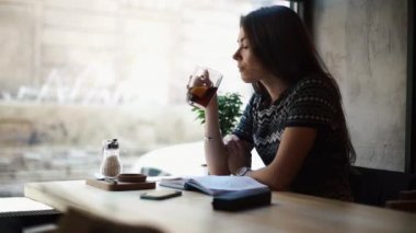 Çekici kız kafenin penceresinden bakarken çay fincanının tadını çıkarıyor. Notlarını okuyor..