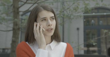 Güzel genç esmer, cep telefonuyla konuşurken gülümsüyor. 4k.