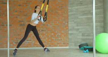 Genç, çekici, sıska kadının uzun pozu spor kıyafetinin kayışları kullanarak atlamasıdır..