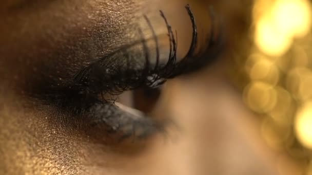 Vrouwelijke knipperende ogen van de Afrikaanse vrouw bedekt met gouden eyeshadows en eyeliner. Close-up weergave. Make-up en fashion concept. — Stockvideo