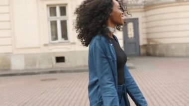 Mutlu gülümseyen çekici Afrikalı kız cadde boyunca yürürken etrafında dönüyor. 4k görüntü.