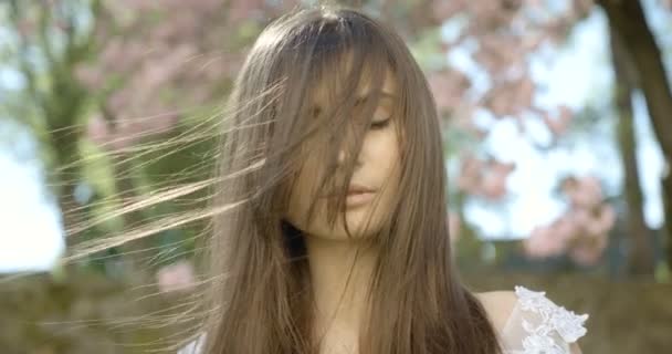 Retrato da bela menina sensível com o cabelo escuro em movimento do vento de pé com os olhos fechados e, em seguida, olhando para a câmera. Filmagem 4k. — Vídeo de Stock