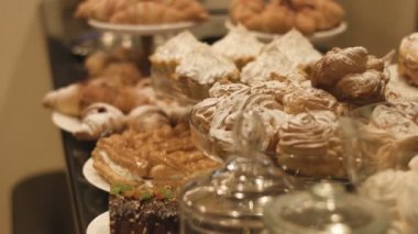 Açık büfe, choux pastası, eklerleri ve diğer güzel görünümlü pastalar gibi hintyağı şekeriyle kaplanmış farklı lezzetli tatlılarla kaplıdır. 4K görüntü. Kimse yok..