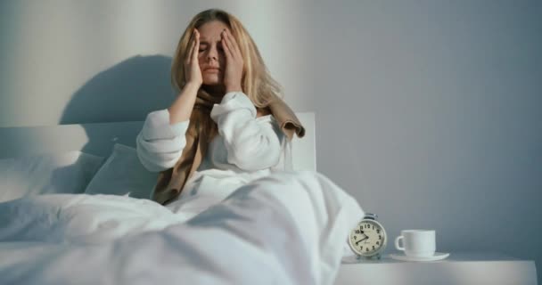 Porträt der kranken blonden Frau, die im Bett liegt. Sie hat schreckliche Kopfschmerzen. 4k. — Stockvideo