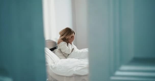 Mujer rubia aislada con frío estornuda y descansa en la cama sola. Imágenes de 4k. — Vídeo de stock